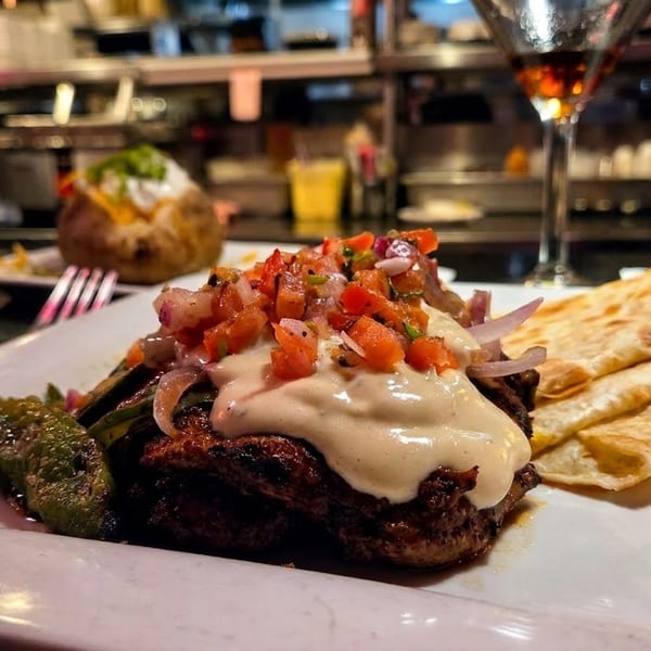 Grilled steak topped with creamy sauce and pico de gallo, served with flatbreads and a pepper.